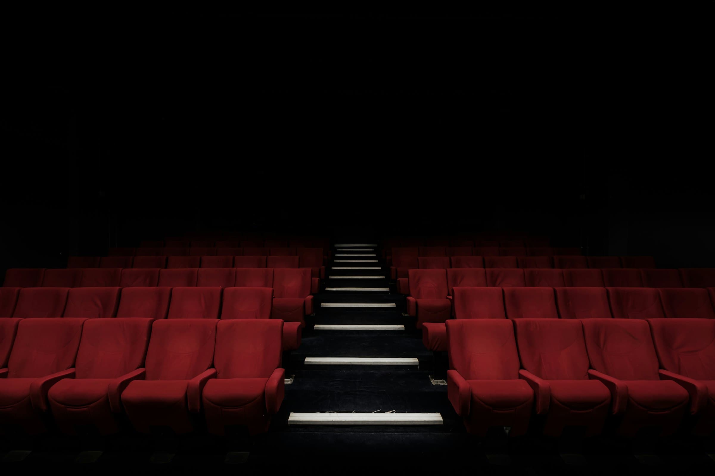 Rows of red cinema seats in a darkened theatre